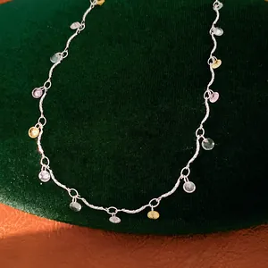 Close-up of elegant silver necklace with colorful round zircon charms on green velvet