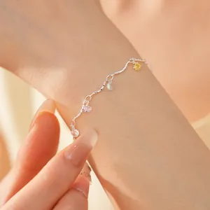 Detailed view of a silver bracelet with colorful zirconia charms on a model's wrist