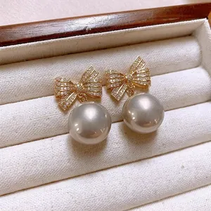Macro view of elegant bow knot zircon earrings with greyish pearl drop