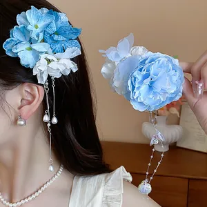 Dettaglio ravvicinato di un fermaglio per capelli a fiore blu con nappe di perle.