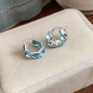 Dettaglio ravvicinato di orecchini a cerchio vintage in argento con zirconi azzurri quadrati
