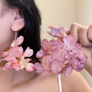 Vista dettagliata di eleganti orecchini a fiore in tessuto oversize con perle su modella