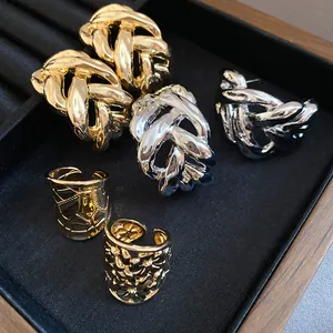 Detailed view of chunky gold and silver metal earrings and floral rings in a jewelry tray