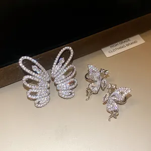 Close-up of sparkling zircon butterfly wing ear clips on a premium textured background