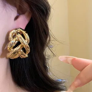 Close-up of a model wearing chunky gold twisted chain earrings in a luxurious style