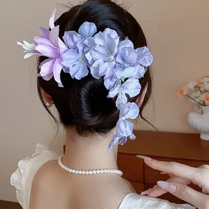 Vista ravvicinata di un'elegante clip per capelli a fiore di stoffa viola in uno chignon