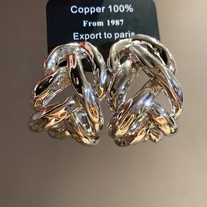Close-up of exaggerated metallic chain C-shape stud earrings in silver finish