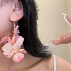 Vista dettagliata di eleganti orecchini a nappa con fiori in tessuto rosa indossati da una modella