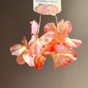 Primo piano squisito di orecchini a nappa con fiori di stoffa rosa e rose in resina