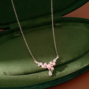 Close-up of elegant necklace with pink pearls and teardrop zircon in green velvet box.