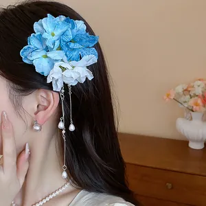 Dettaglio di un'elegante clip per capelli con fiori blu e nappe di perle lunghe su una modella.