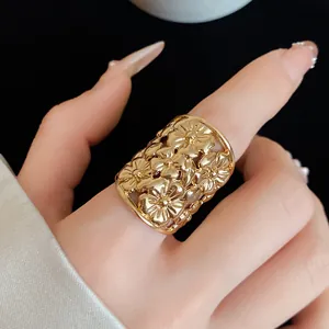 Close-up of a gold-colored wide ring featuring a delicate hollow floral pattern.