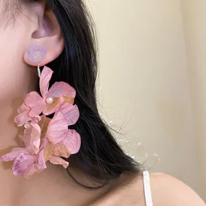 Vista dettagliata di eleganti orecchini a fiore in tessuto rosa con perle per donna