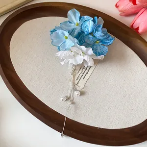 Dettaglio di un fermaglio per capelli a fiori in tessuto blu e bianco con nappe di perle