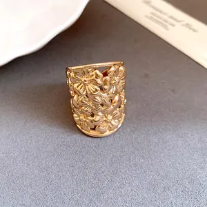 Close-up of a high-end gold plated wide band ring with delicate 3D floral cutout design