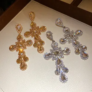 Dettaglio di orecchini a croce in oro e argento con cristalli scintillanti e strass