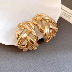 Close-up of chunky gold chain link C-shaped stud earrings with a polished metal finish