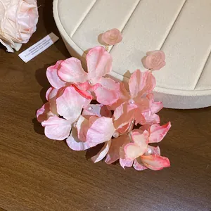 Dettaglio di orecchini a fiore in tessuto rosa con rose in resina e perle fini