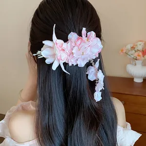 Dettaglio di un elegante fermaglio per capelli in tessuto rosa con nappa su lunghi capelli neri.