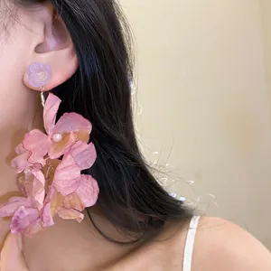 Primo piano di orecchini a fiore in tessuto rosa con perno a rosa in resina