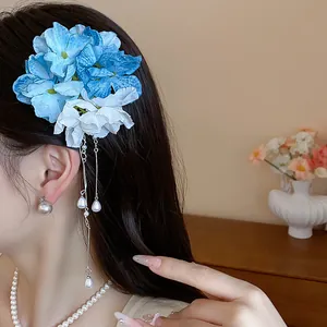 Primo piano di fermaglio per capelli con fiori di stoffa blu e nappe di perle