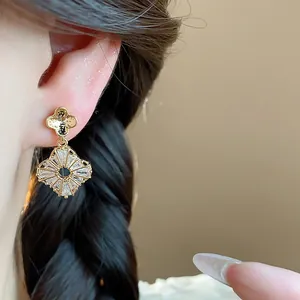 Primo piano dettagliato di eleganti orecchini a fiori in zircone scintillante dorato
