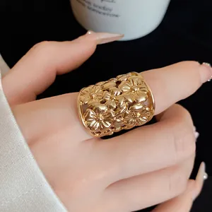 Close-up of a wide gold-colored ring with an intricate floral hollow-out design