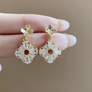 Primo piano di eleganti orecchini a lobo a fiore in oro con brillanti zirconi cubici