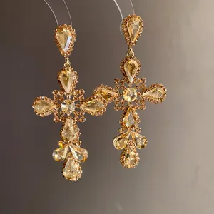 Vista dettagliata di orecchini a croce d'oro di lusso con strass a goccia scintillanti.