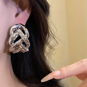 Close-up detail view of a chunky silver woven chain earring worn on ear with dark hair