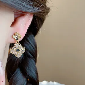 Eleganti orecchini vintage dorati con fiori in zircone indossati sull'orecchio.
