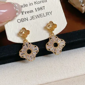 Dettaglio di orecchini a lobo a fiore in oro con brillanti pendenti a raggiera in zirconi