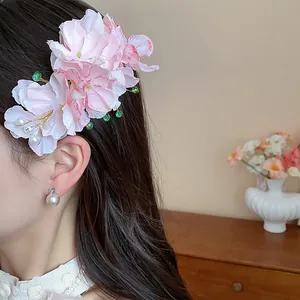 Vista dettagliata di un elegante fermaglio per capelli a fiore in tessuto rosa con perle.