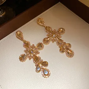 Vista dettagliata di orecchini a croce con strass champagne e pendenti a goccia
