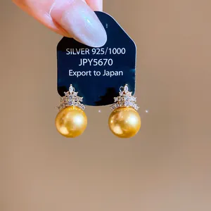 Close-up view of elegant gold pearl earrings with sparkling zircon geometric accents