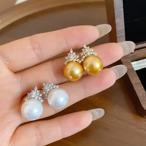 Close-up of elegant zircon and pearl stud earrings in gold and silver tones