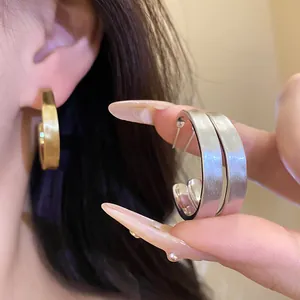 Primo piano di eleganti orecchini a cerchio a C spazzolati in oro 18 carats e argento