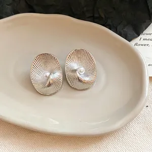Detailed view of vintage silver-tone oval stud earrings with pearl and spiral texture
