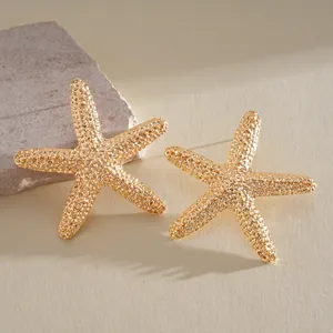 Detailed macro view of textured gold-toned starfish stud earrings on a natural stone