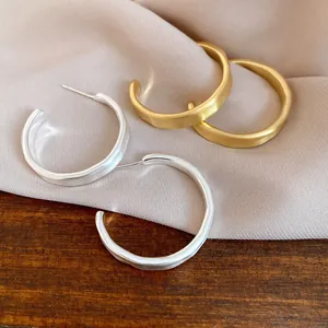 Dettaglio della trama spazzolata di orecchini a cerchio a forma di C placcati oro e argento