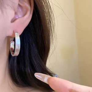 Primo piano di un orecchino a C in argento spazzolato sull'orecchio di una modella.