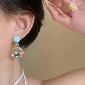 Primo piano di orecchini a sfera in vetro con pois blu chiaro stile foresta