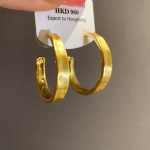 Dettaglio delle orecchini a cerchio a forma di C in oro 18 carati spazzolato con etichetta.