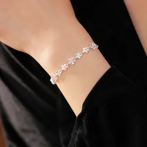 Bracelet délicat en zircon avec fleurs et perles pour femme porté au poignet style élégant.