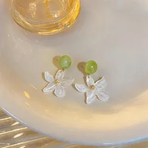 Dettaglio ravvicinato di orecchini stile foresta con perla verde e petali bianchi traslucidi