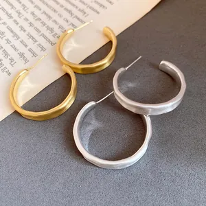 Dettaglio di orecchini a cerchio a C spazzolati e opachi in oro e argento placcato