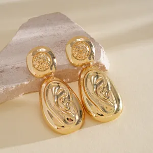 Detail shot of vintage gold-finished oval drop earrings with artistic relief design.