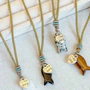 Detailed close-up of fish-shaped stone pendants and heart charms on woven necklaces