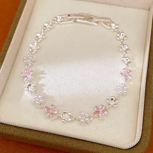 Élégant bracelet argenté avec breloques fleurs roses et détails de perles blanches