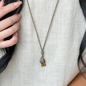 Close-up detail of a stone fish pendant and engraved heart charm on a woven rope necklace